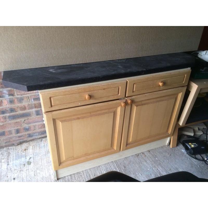 Old kitchen cAbinet with dark work surface.