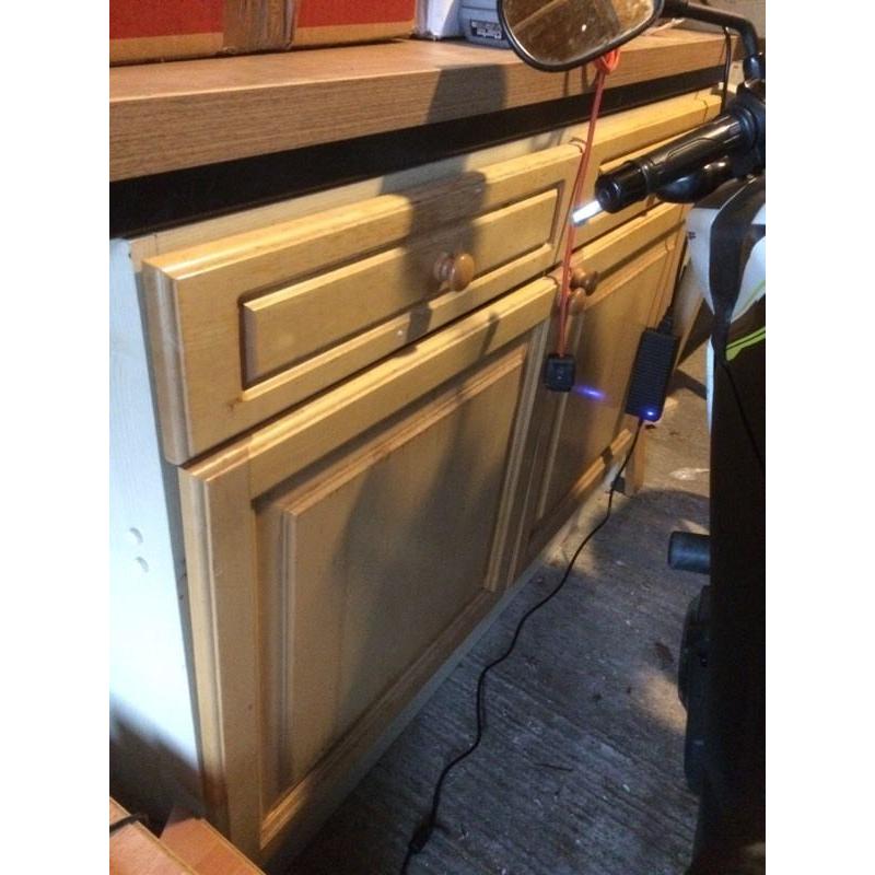 Old kitchen cAbinet with dark work surface.